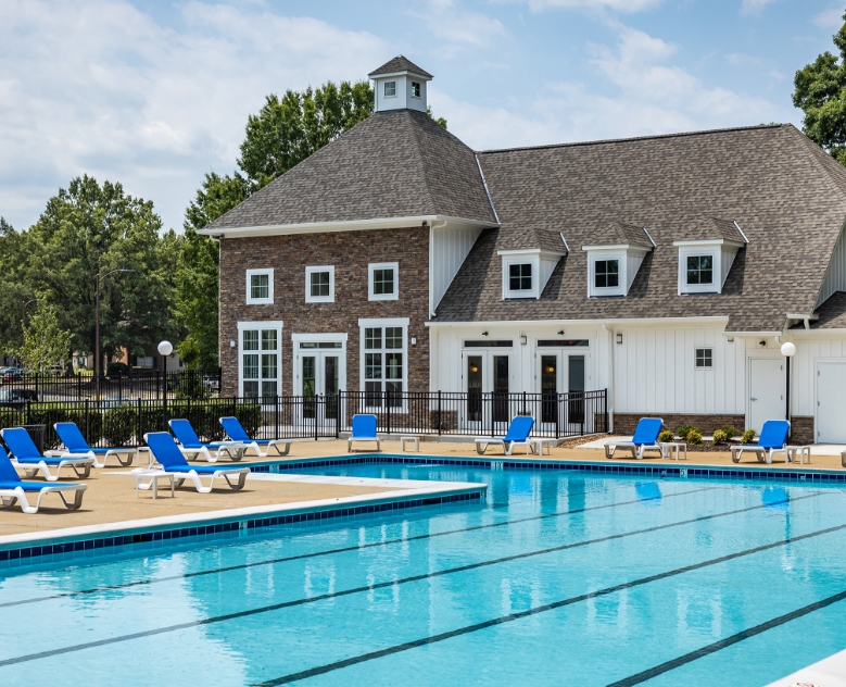 view of clubhouse with pool and blue lounge chairs in the foreground at The Residences at Brookside